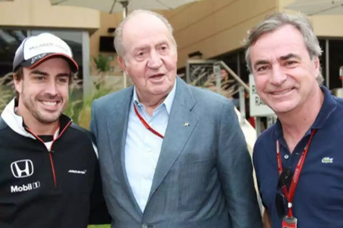 Tres hombres posan juntos al aire libre, uno de ellos lleva una gorra y ropa deportiva, otro viste un traje y el tercero lleva una camiseta polo.