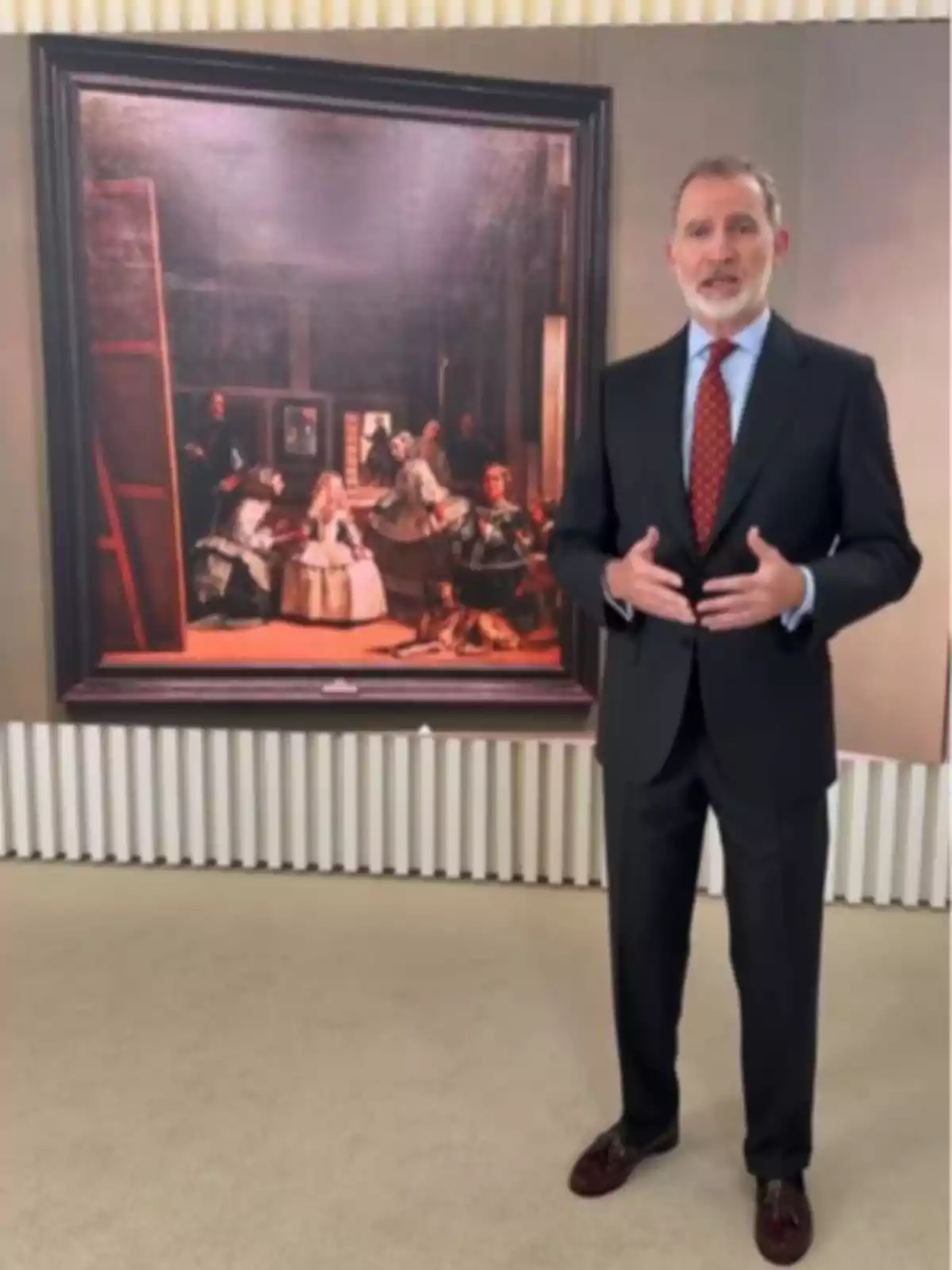 El rey Felipe VI de traje oscuro y corbata roja posando frente al cuadro Las Meninas de Velázquez El rey Felipe VI de traje oscuro y corbata roja posando frente al cuadro Las Meninas de Velázquez