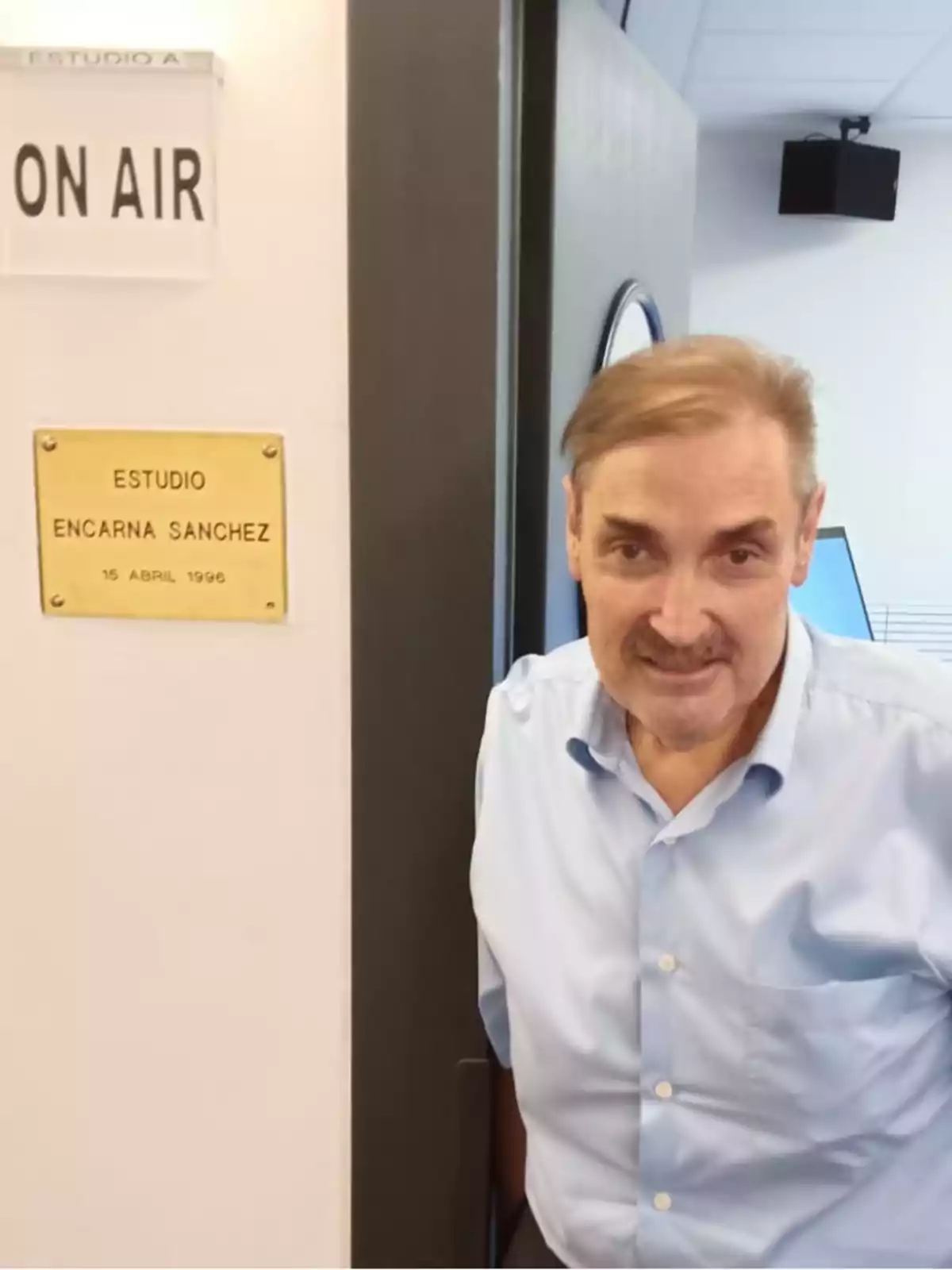 Un hombre de pie junto a la puerta de un estudio de radio con un letrero que dice 