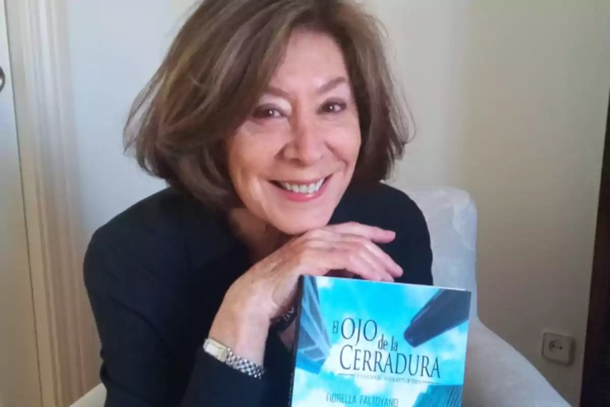 Una mujer sonriente sostiene un libro titulado 