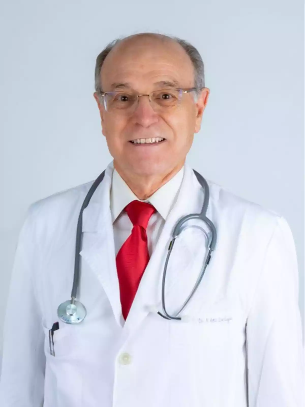 Un médico con bata blanca, corbata roja y estetoscopio alrededor del cuello.