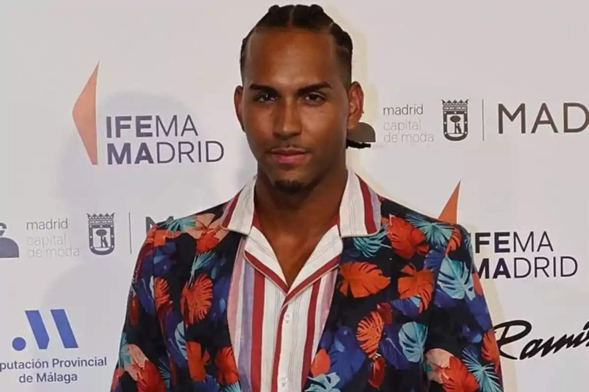 Yulen Pereira, con trenzas y barba, vestido con una chaqueta de colores vivos y camisa a rayas, posando en el desfile de Félix Ramiro Yulen Pereira, con trenzas y barba, vestido con una chaqueta de colores vivos y camisa a rayas, posando en el desfile de Félix Ramiro