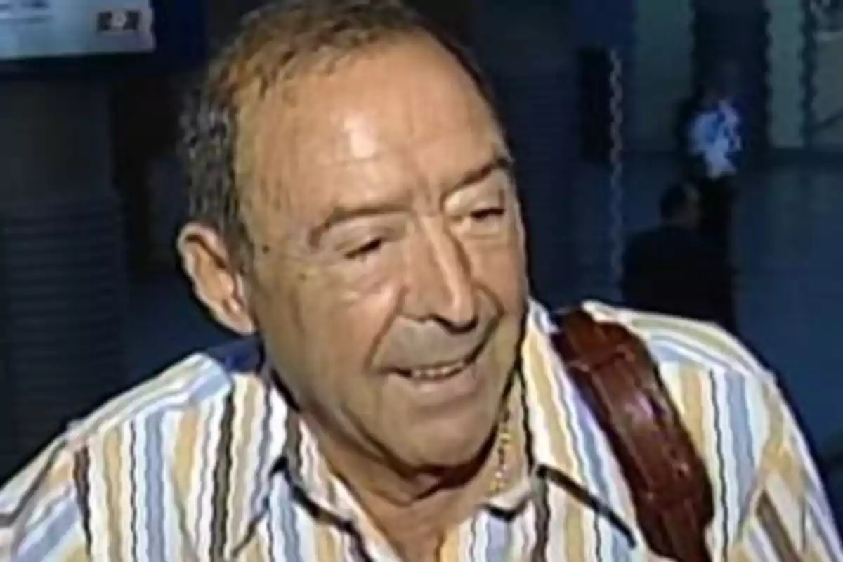 Un hombre mayor con camisa de rayas sonríe mientras mira hacia un lado en un entorno interior. Un hombre mayor con camisa de rayas sonríe mientras mira hacia un lado en un entorno interior.