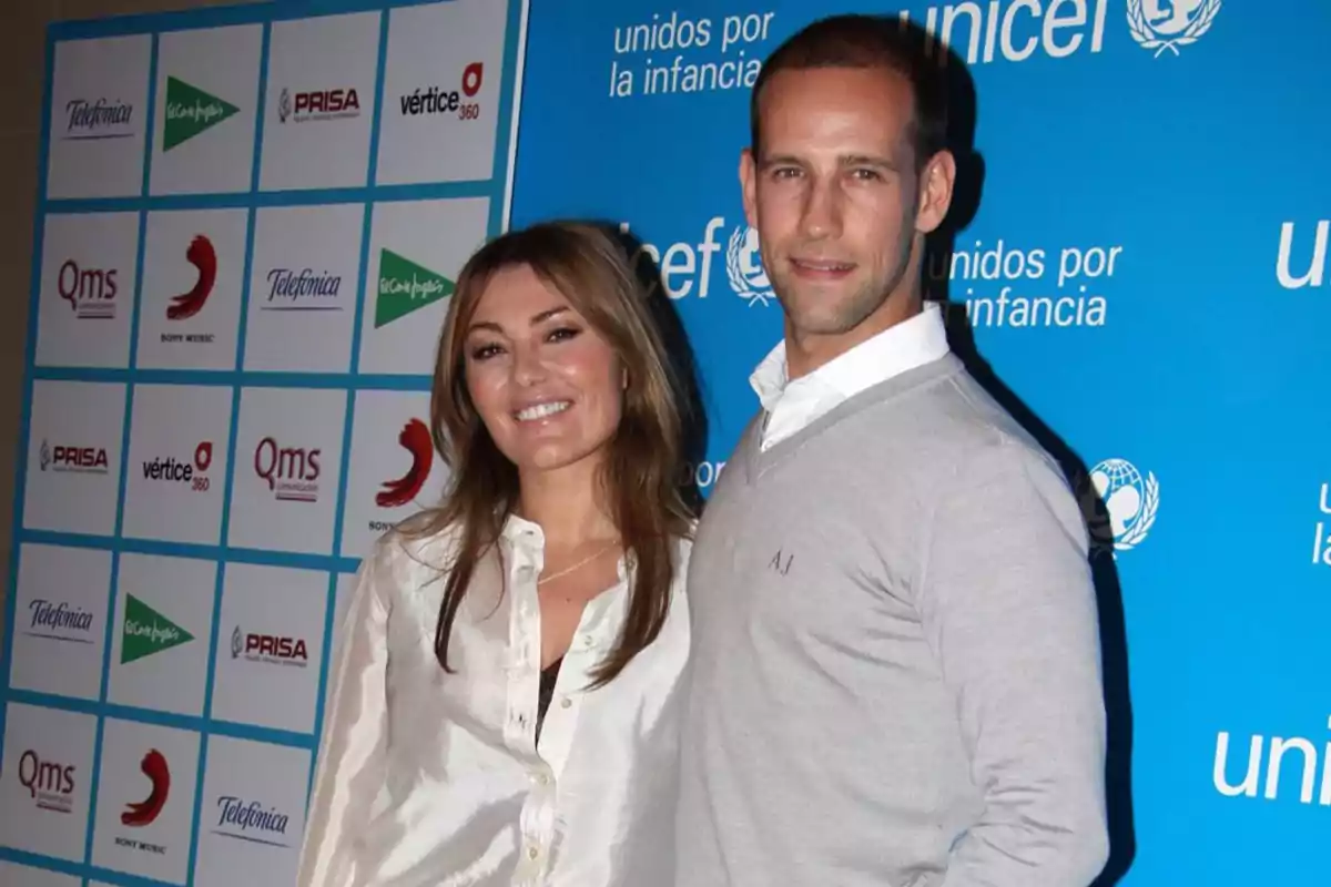 Una pareja sonríe posando frente a un fondo azul con logotipos de Unicef y varias marcas. Una pareja sonríe posando frente a un fondo azul con logotipos de Unicef y varias marcas.