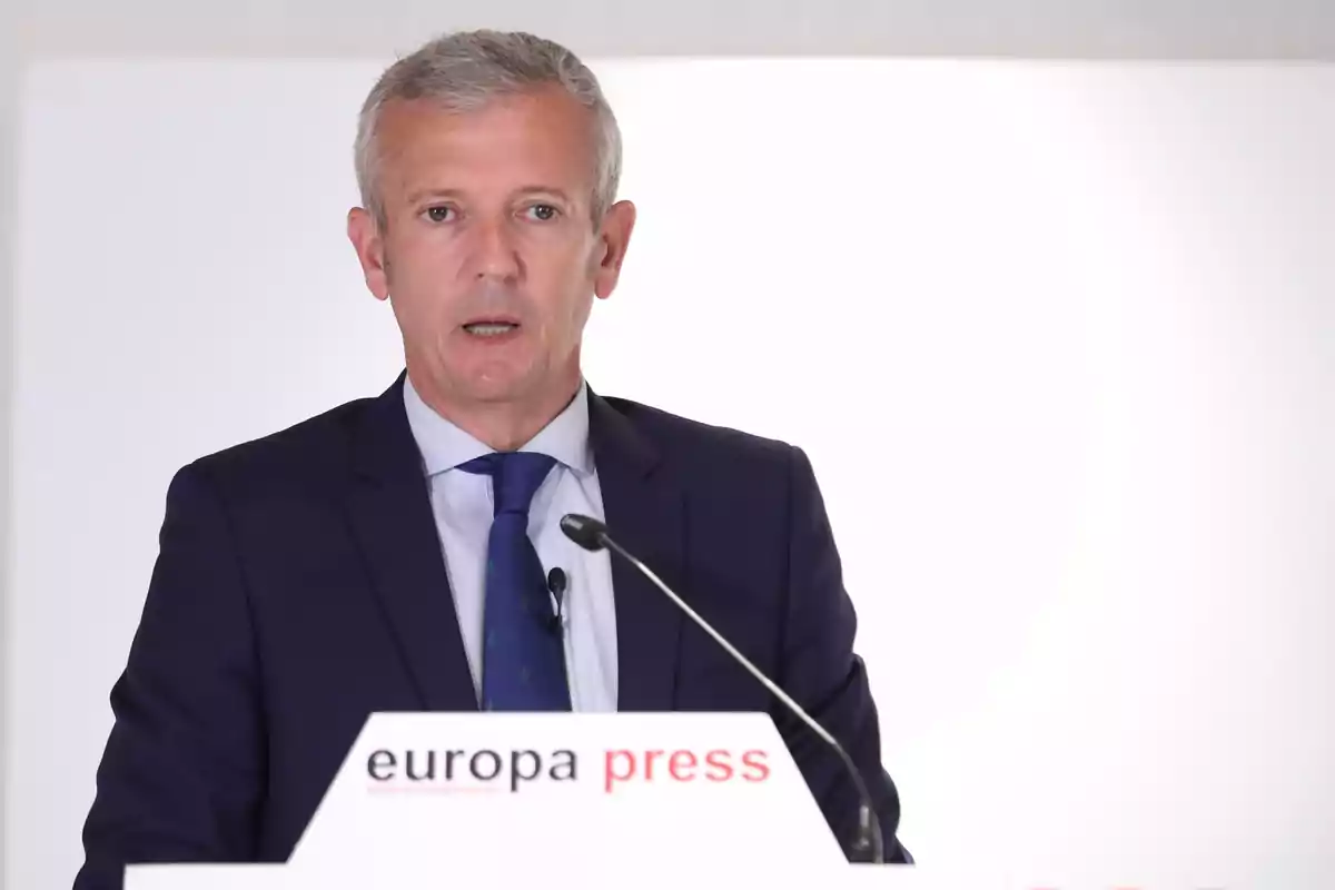Hombre de cabello canoso con traje azul hablando en un podio de europa press Hombre de cabello canoso con traje azul hablando en un podio de europa press