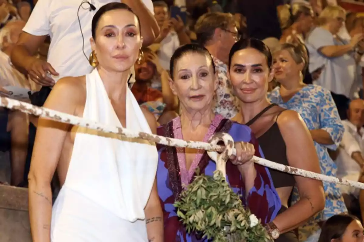 Tres mujeres posan juntas en un evento al aire libre rodeadas de una multitud. Tres mujeres posan juntas en un evento al aire libre rodeadas de una multitud.