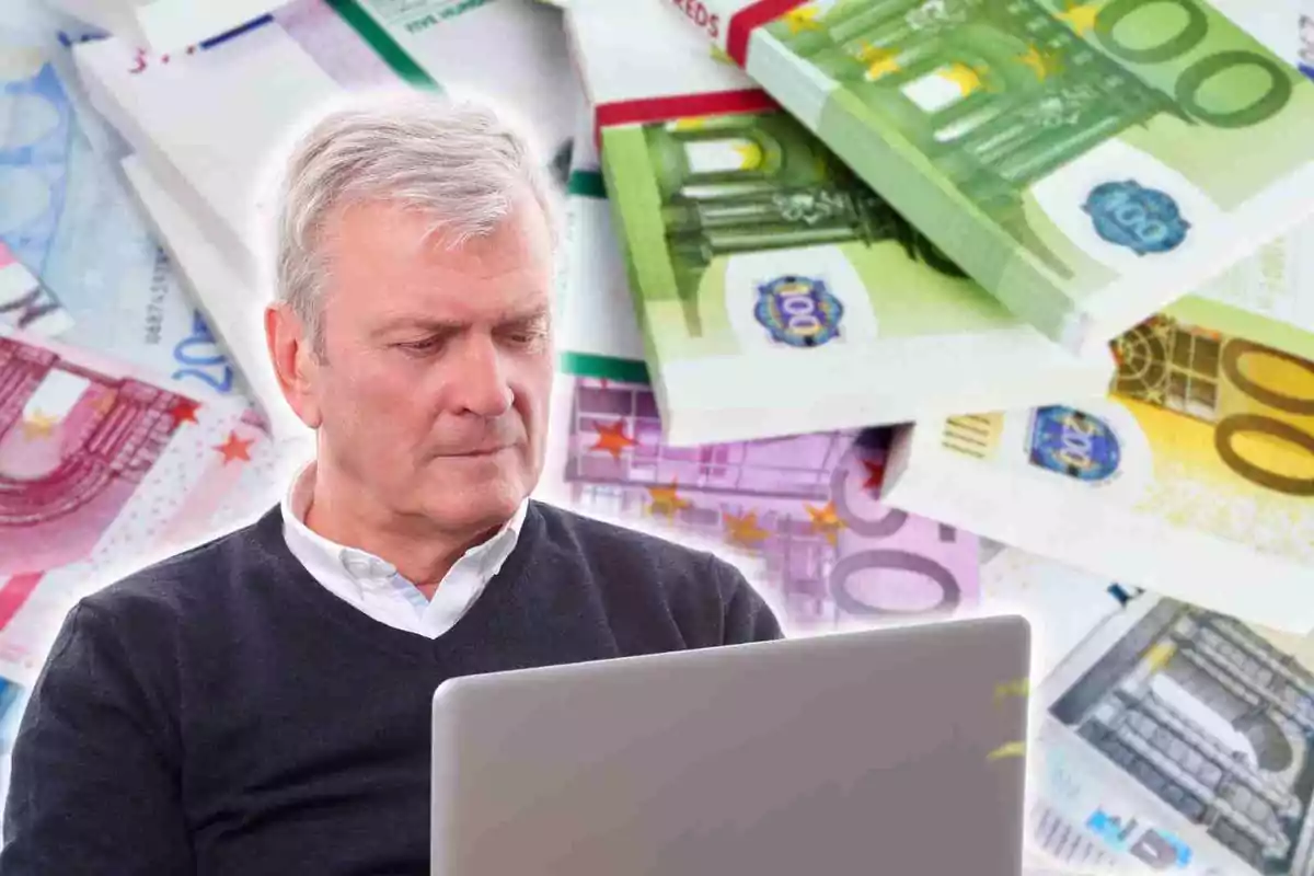 Hombre mayor usando una computadora portátil con billetes de euro en el fondo.