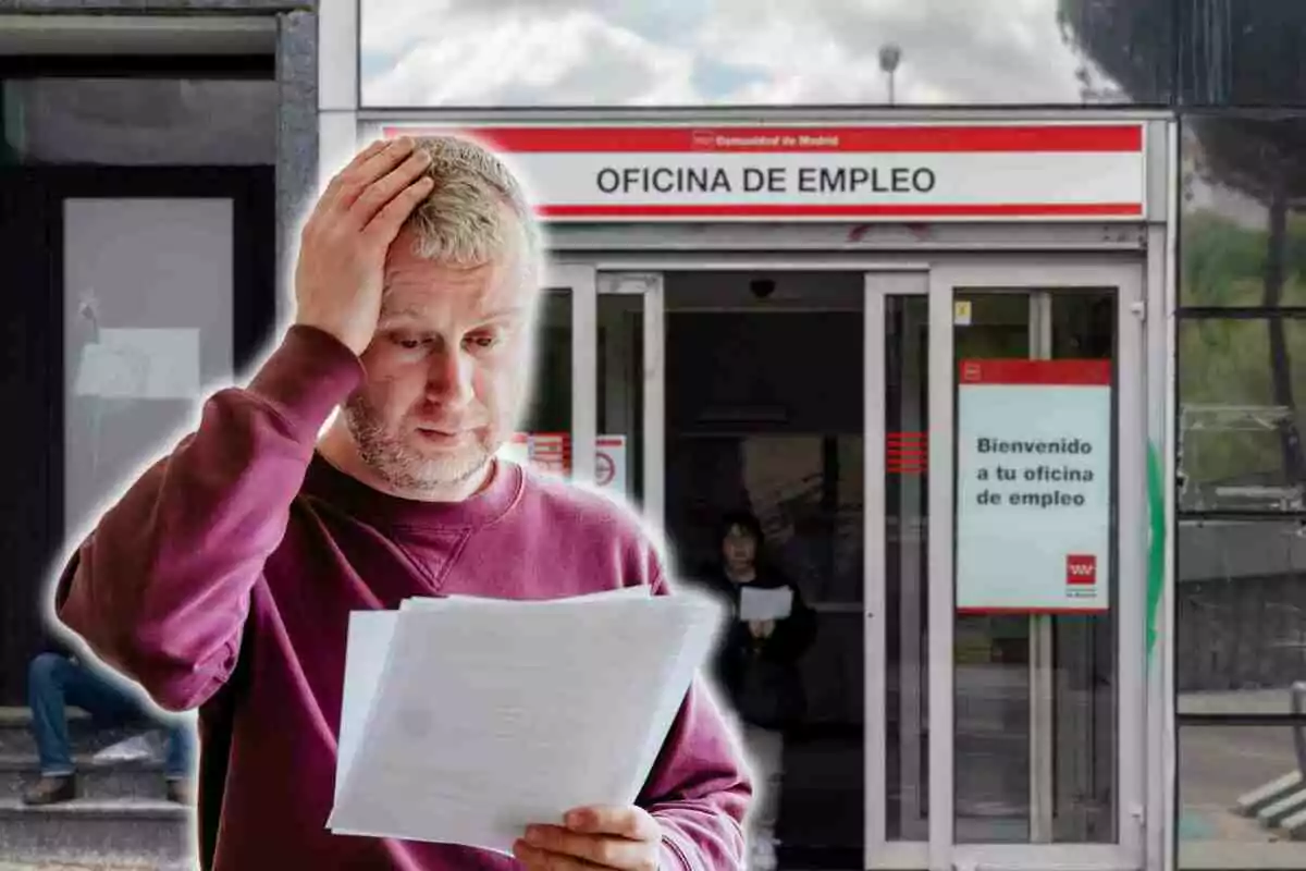 Un hombre con expresión preocupada sostiene unos papeles frente a una oficina de empleo en Madrid.