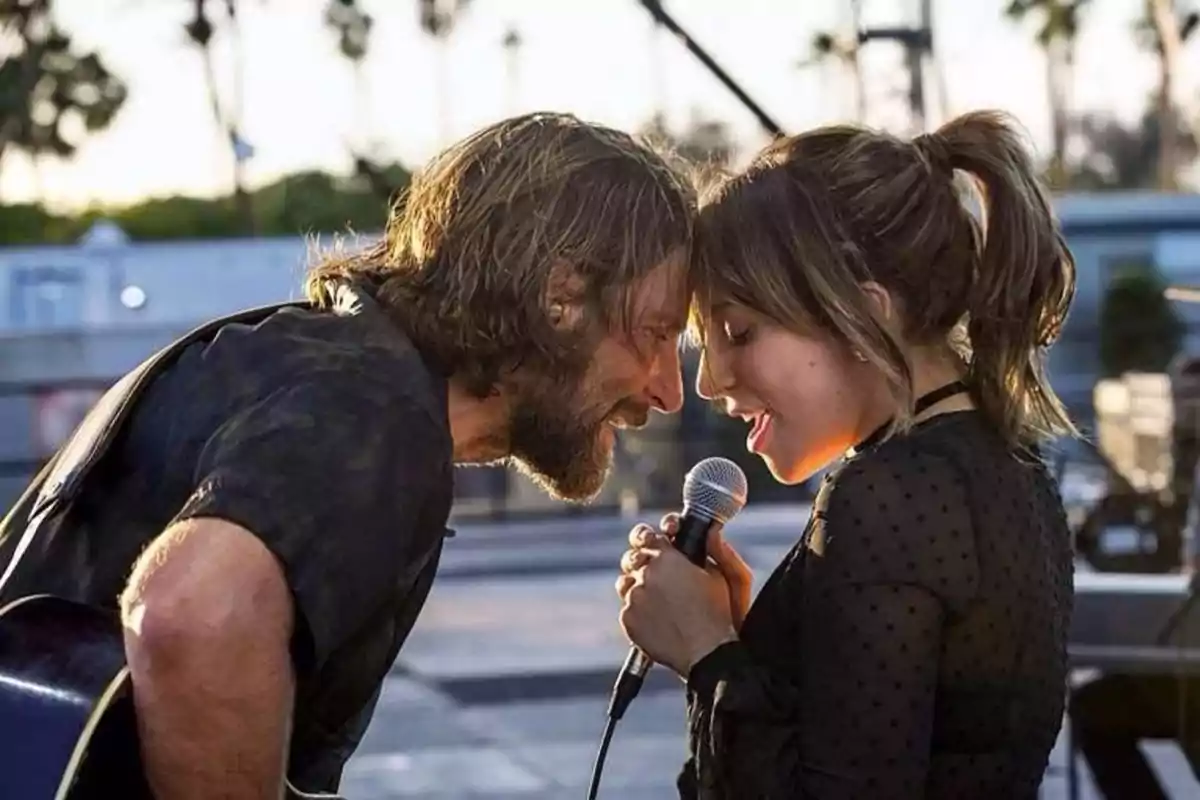 Dos personas cantando juntas en un escenario al aire libre, compartiendo un momento íntimo mientras sostienen un micrófono. Dos personas cantando juntas en un escenario al aire libre, compartiendo un momento íntimo mientras sostienen un micrófono.