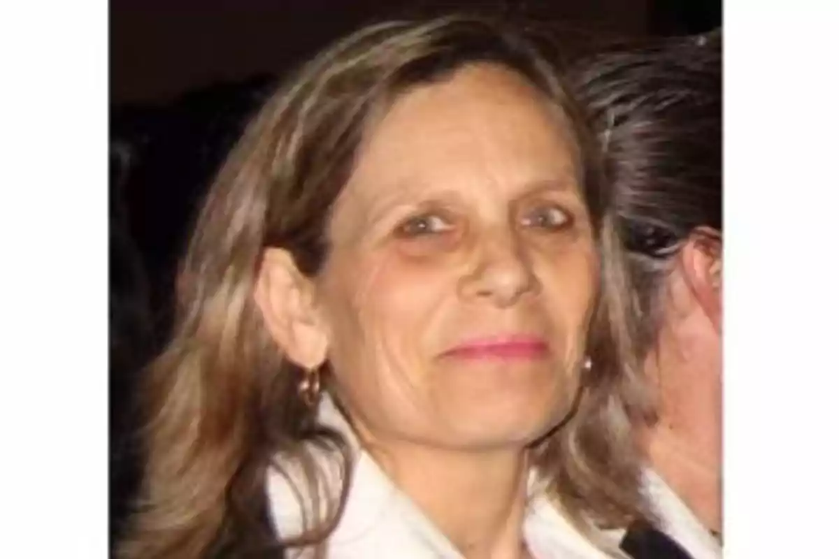 Una mujer de cabello castaño claro y expresión serena mira hacia la cámara.