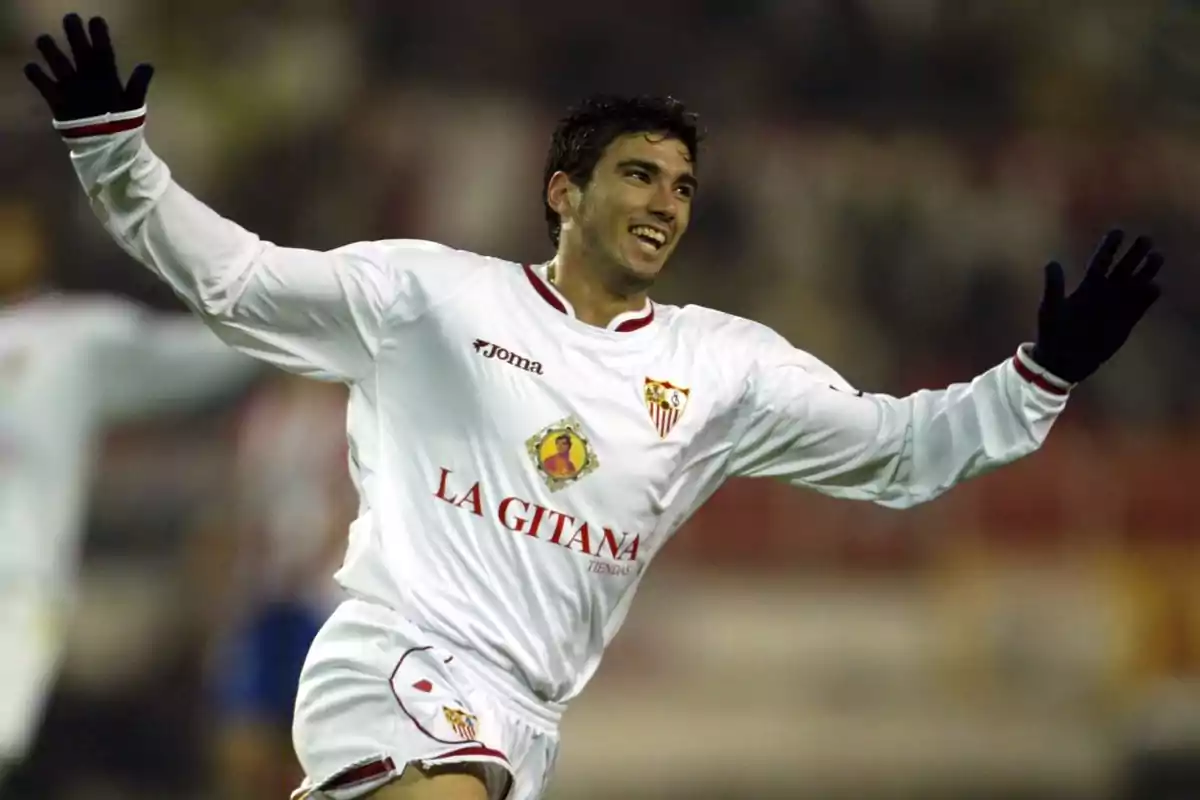 Futbolista del Sevilla celebrando un gol con los brazos abiertos y vistiendo uniforme blanco Futbolista del Sevilla celebrando un gol con los brazos abiertos y vistiendo uniforme blanco