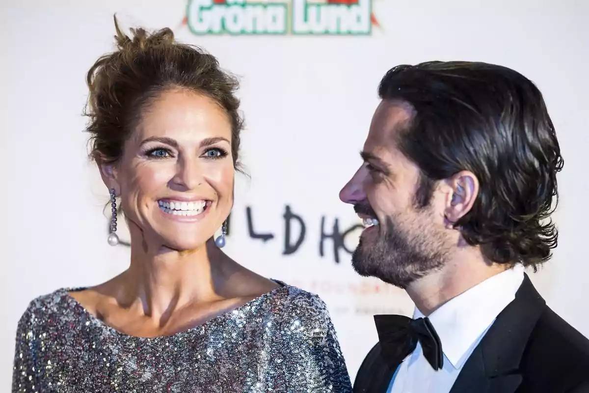 Una mujer con vestido brillante y un hombre con esmoquin sonríen en un evento elegante Una mujer con vestido brillante y un hombre con esmoquin sonríen en un evento elegante