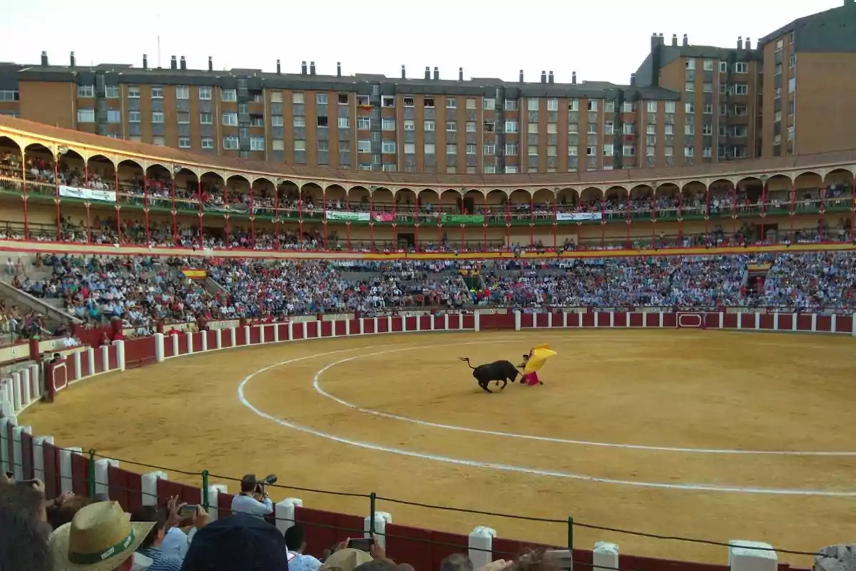 Una plaza de toros llena de espectadores con un torero y un toro en el centro del ruedo. Una plaza de toros llena de espectadores con un torero y un toro en el centro del ruedo.
