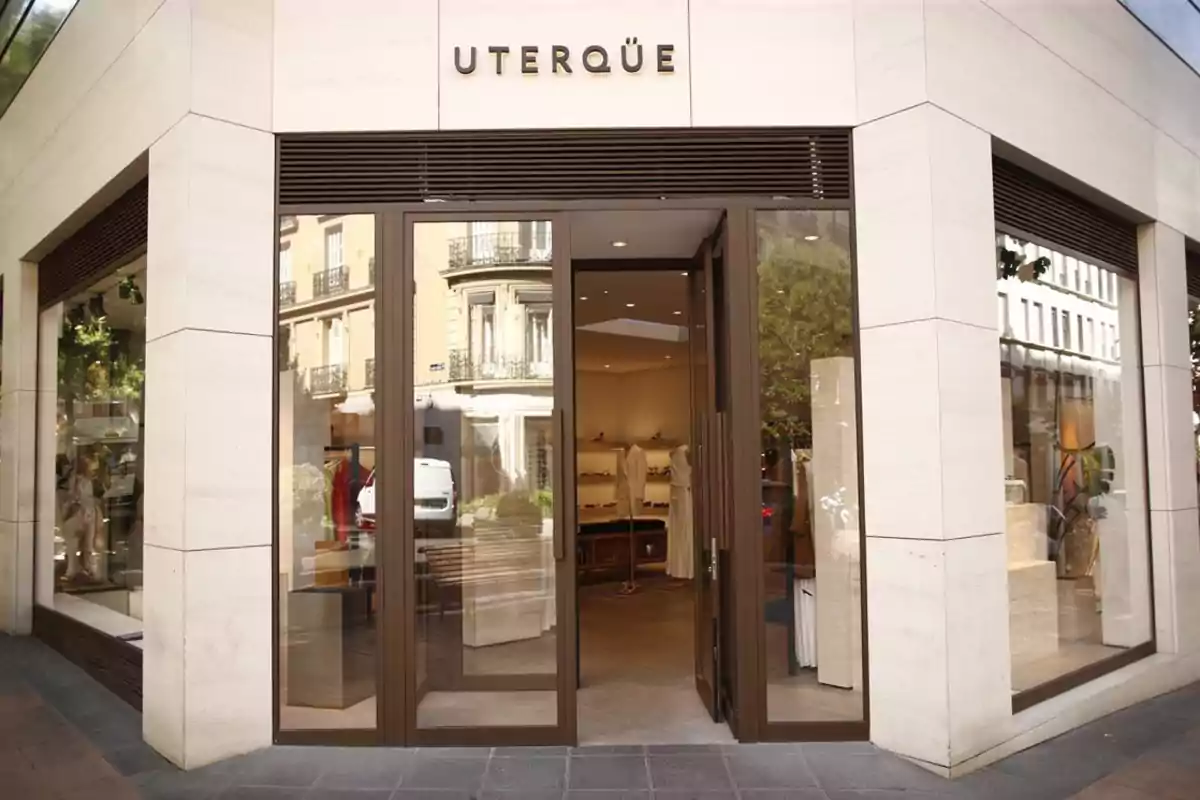 Fachada de una tienda Uterqüe con puertas de cristal abiertas y escaparates mostrando ropa y accesorios Fachada de una tienda Uterqüe con puertas de cristal abiertas y escaparates mostrando ropa y accesorios