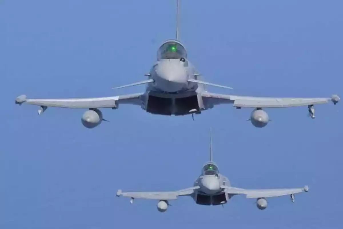 Dos aviones de combate volando en formación sobre un cielo despejado. Dos aviones de combate volando en formación sobre un cielo despejado.