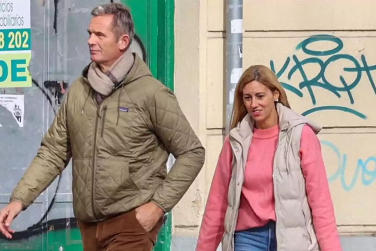 Un hombre y una mujer caminan juntos por la calle vestidos con ropa de abrigo casual y fondo con grafitis. Un hombre y una mujer caminan juntos por la calle vestidos con ropa de abrigo casual y fondo con grafitis.