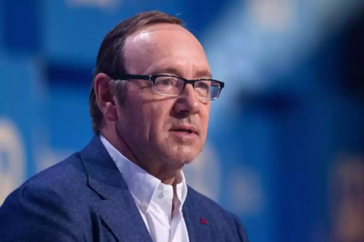Un hombre con gafas y traje azul en un entorno de fondo azul. Un hombre con gafas y traje azul en un entorno de fondo azul.
