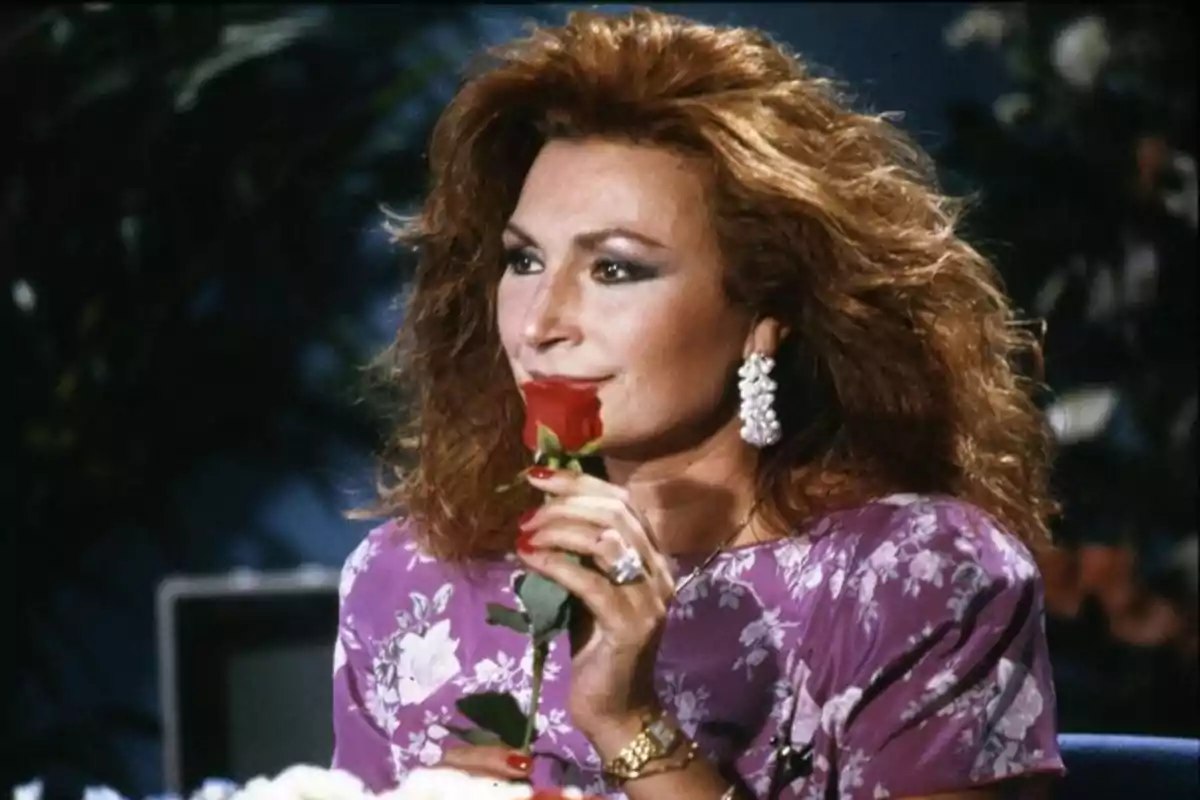 Mujer pelirroja con vestido morado y aretes grandes sosteniendo una rosa roja frente a su rostro Mujer pelirroja con vestido morado y aretes grandes sosteniendo una rosa roja frente a su rostro