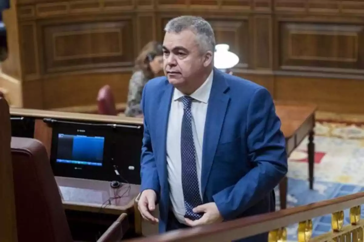 Hombre de cabello canoso con traje azul y corbata de lunares en un recinto parlamentario Hombre de cabello canoso con traje azul y corbata de lunares en un recinto parlamentario