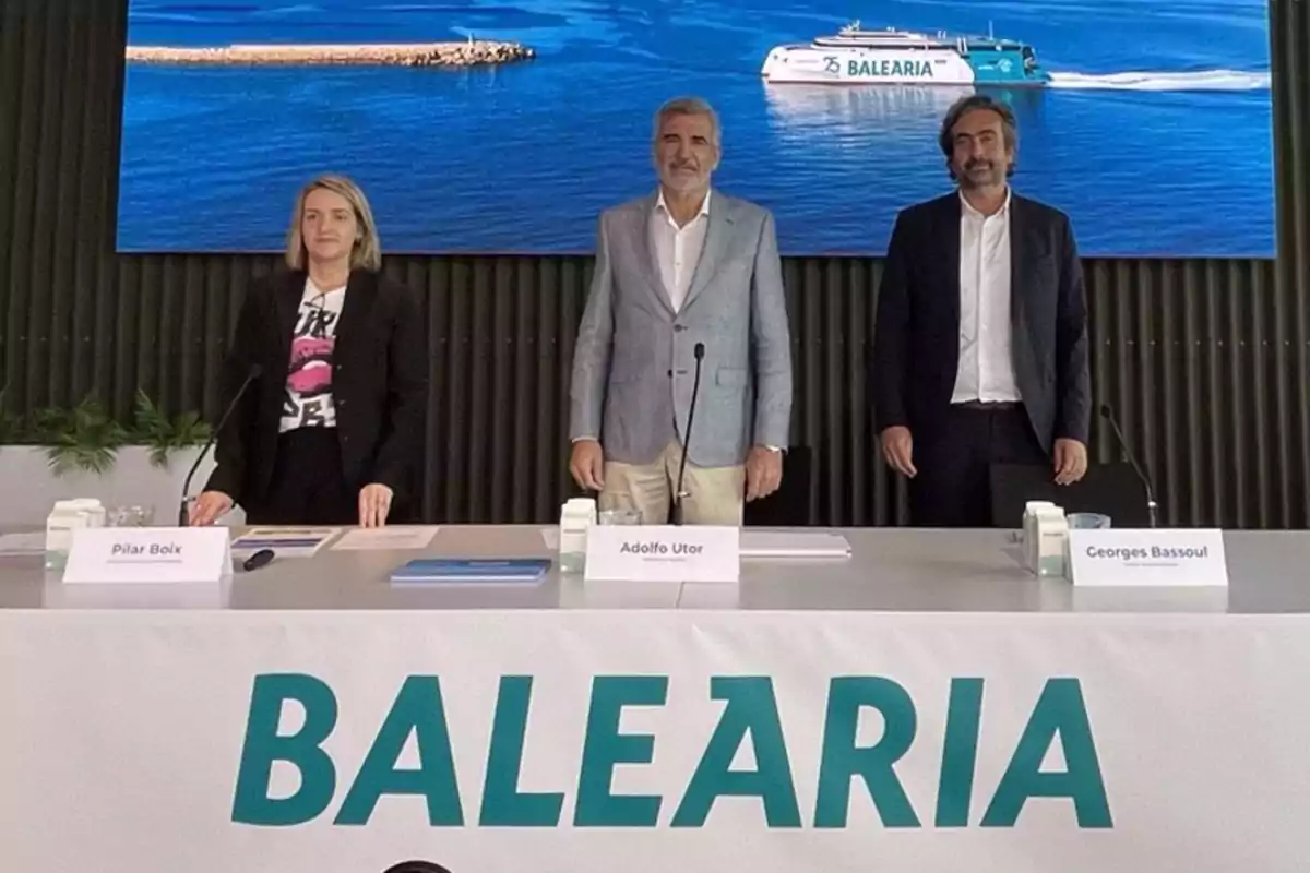 Tres personas de pie detrás de una mesa con un cartel que dice Tres personas de pie detrás de una mesa con un cartel que dice