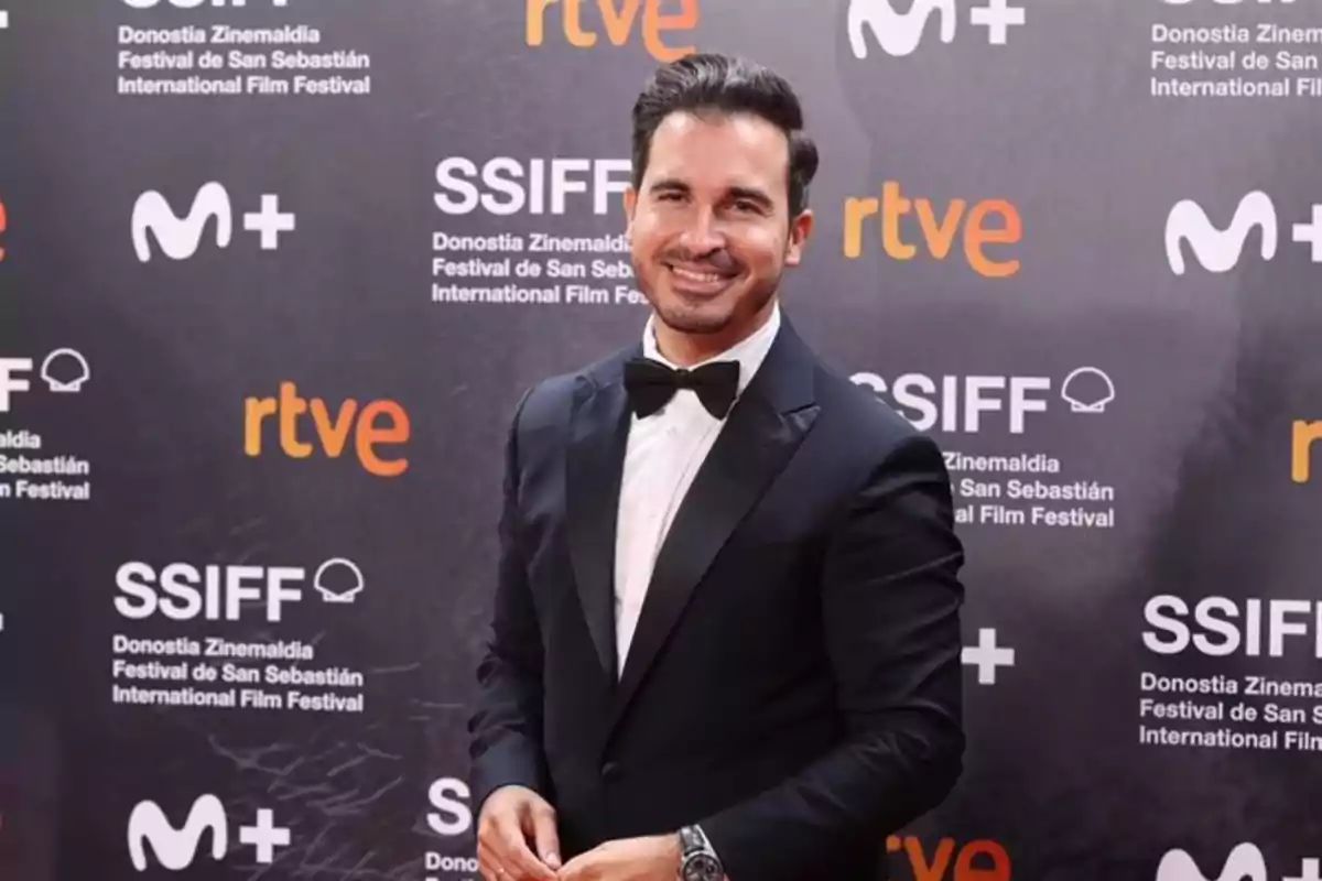 Un hombre con esmoquin sonríe en la alfombra roja del Festival Internacional de Cine de San Sebastián.