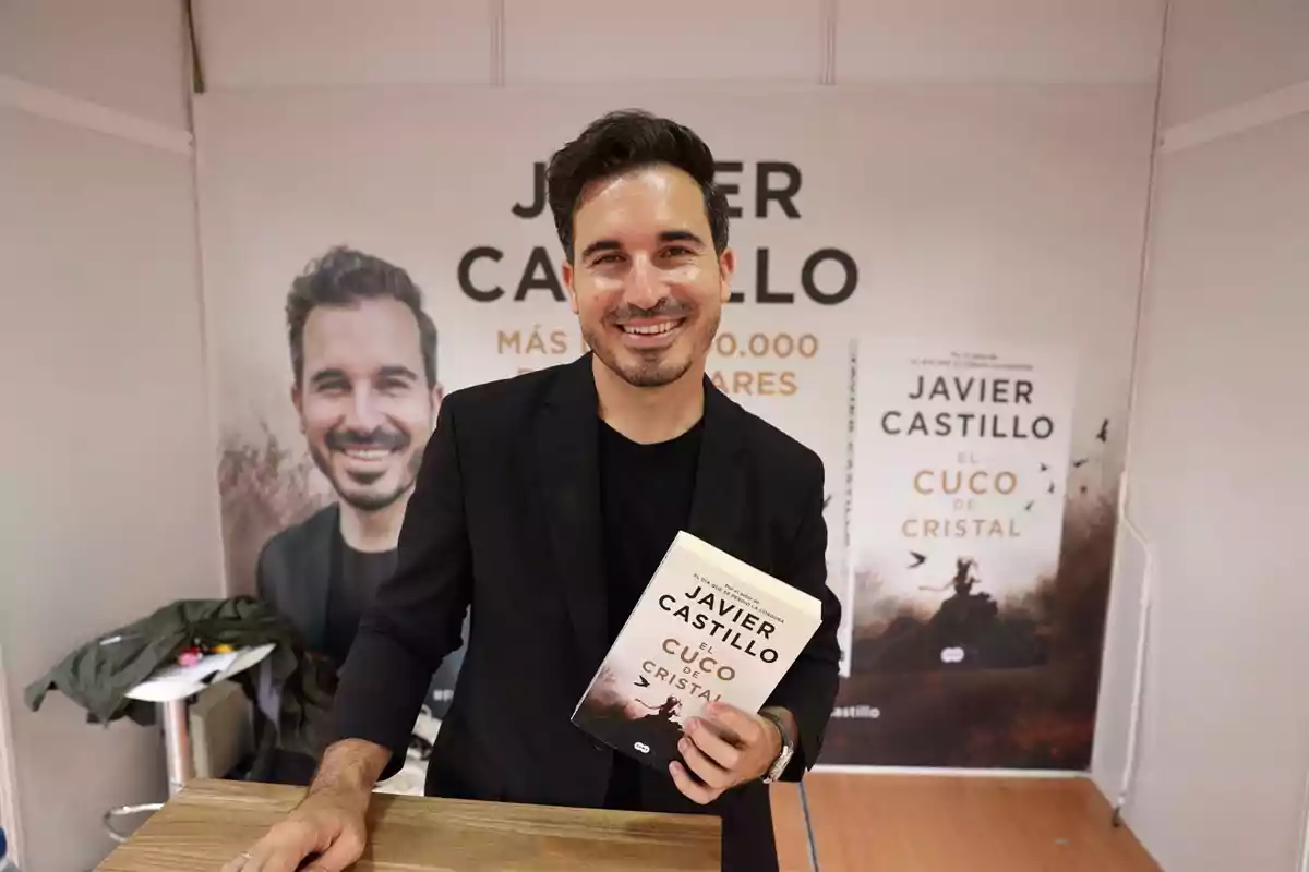 Un hombre sonriente sostiene un libro titulado 