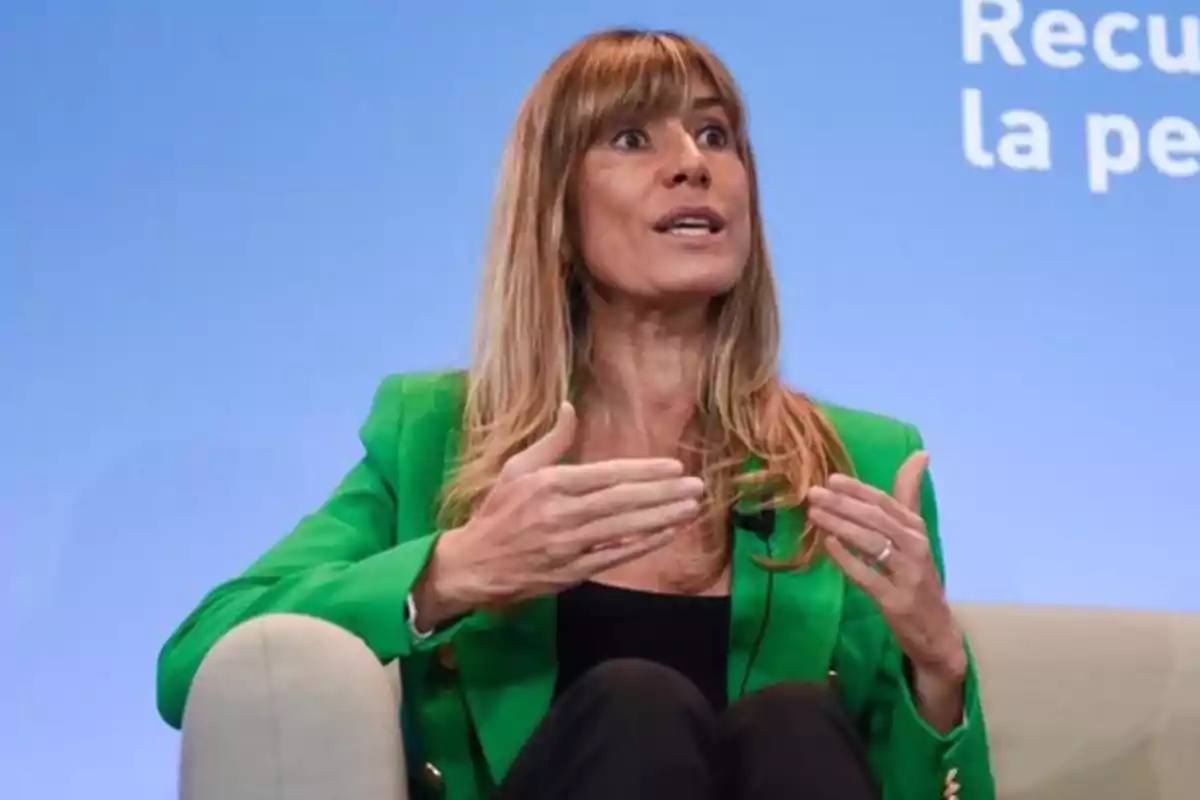 Una mujer con chaqueta verde gesticula mientras habla en un evento. Una mujer con chaqueta verde gesticula mientras habla en un evento.
