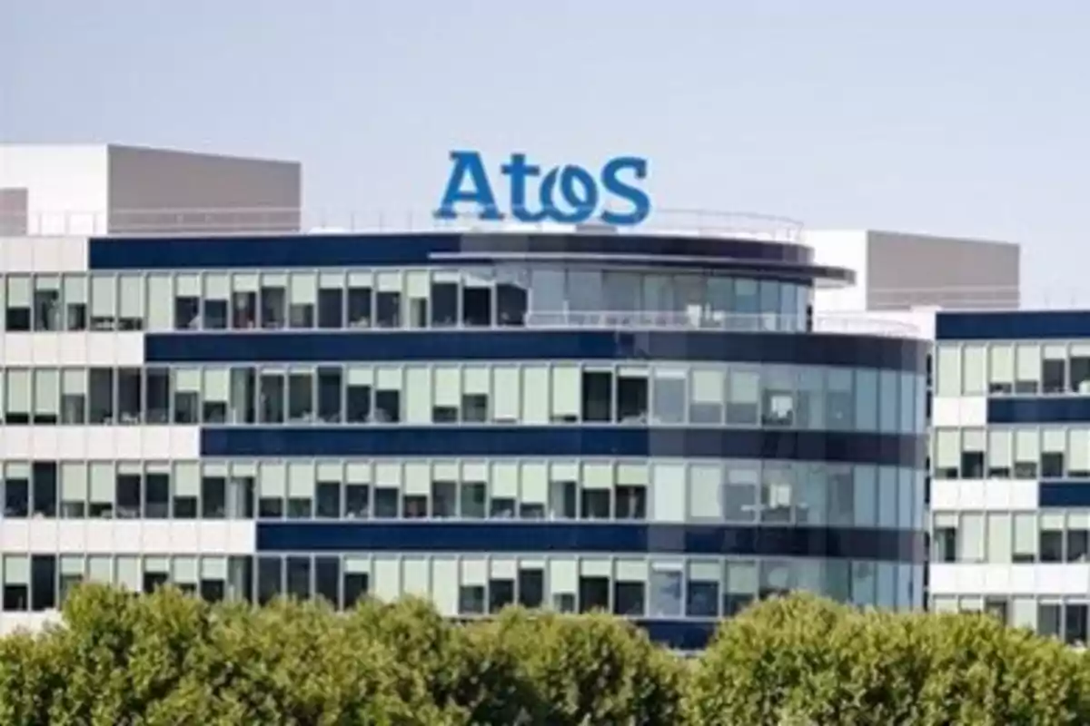 Edificio moderno con fachada de vidrio y logo de Atos en la parte superior.