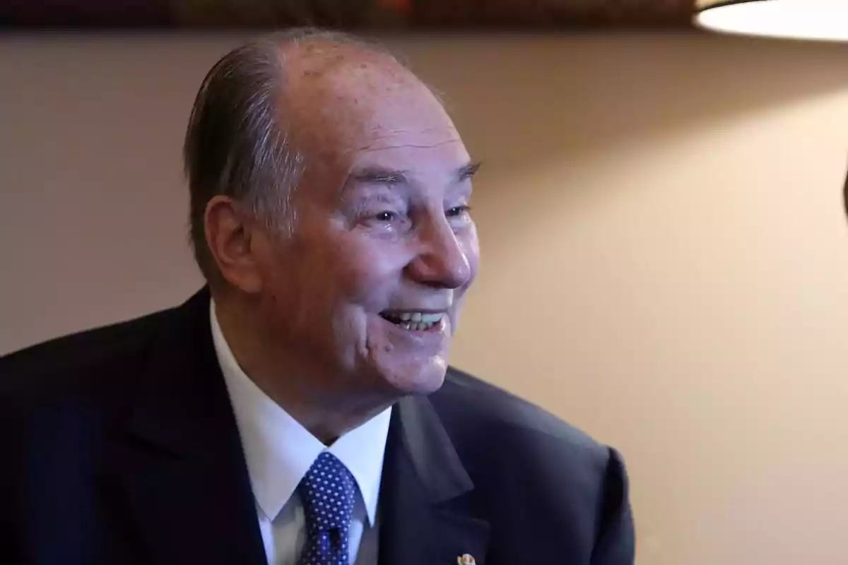 An older man smiling and wearing a dark suit with a blue tie. An older man smiling and wearing a dark suit with a blue tie.
