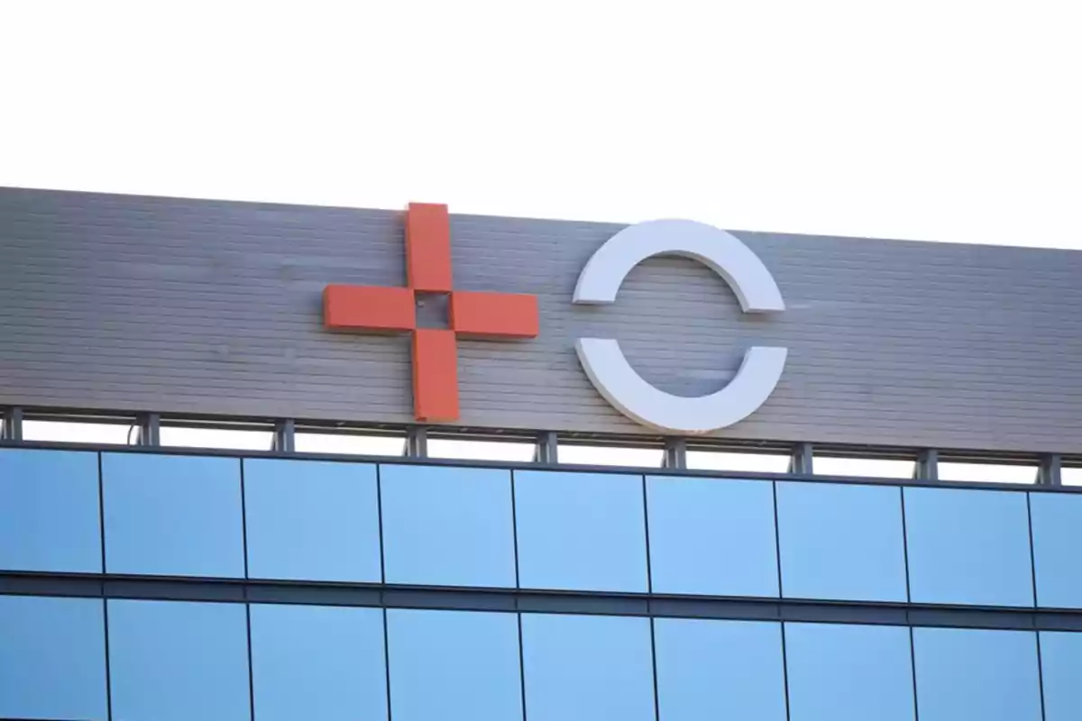 Fachada de edificio moderno con un símbolo de cruz roja y una letra C blanca en la parte superior Fachada de edificio moderno con un símbolo de cruz roja y una letra C blanca en la parte superior