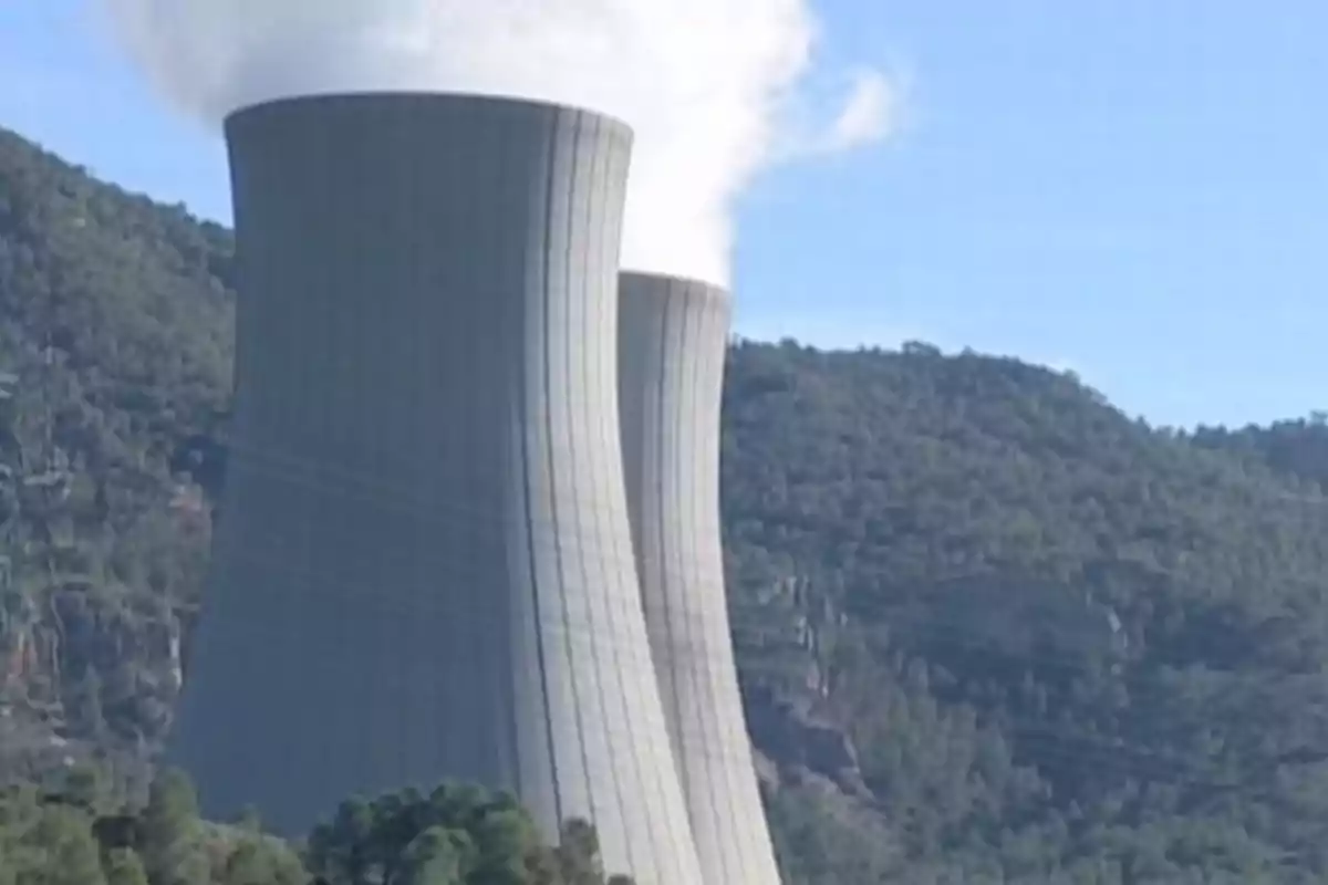 Torres de refrigeración de una planta nuclear con humo saliendo en un entorno montañoso. Torres de refrigeración de una planta nuclear con humo saliendo en un entorno montañoso.