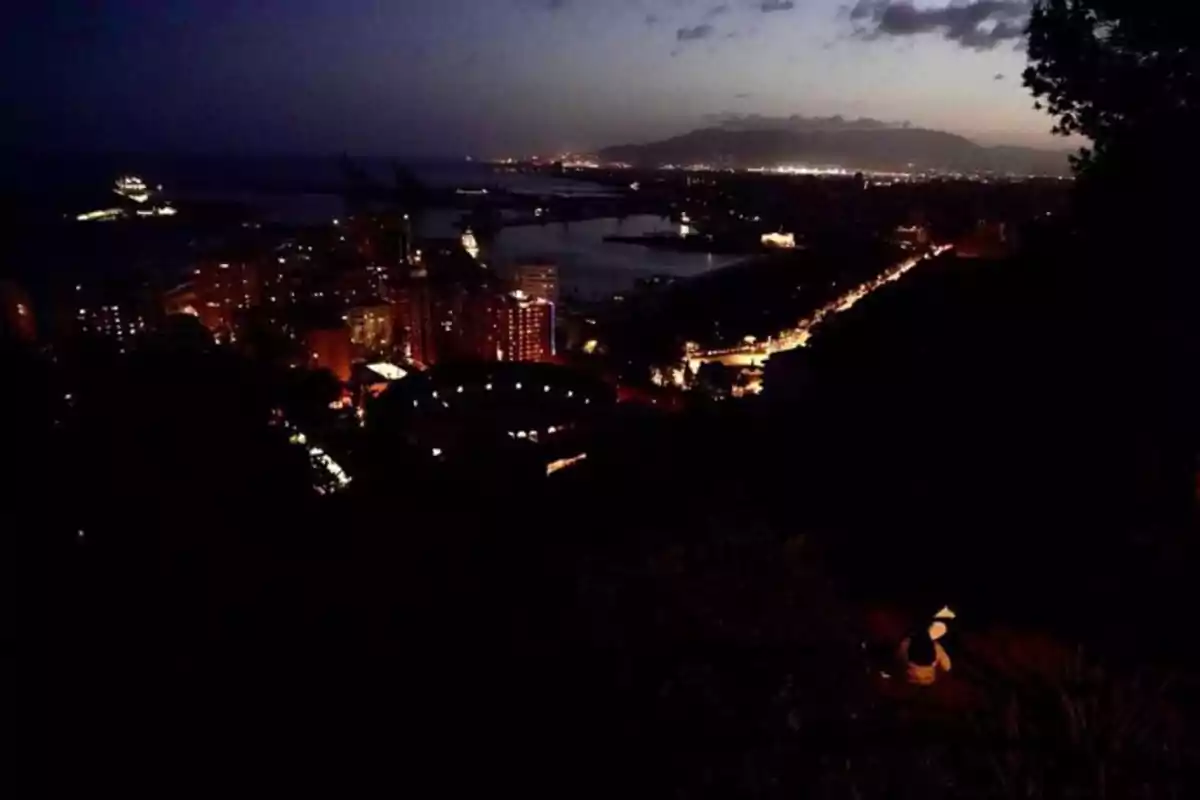 Vista nocturna de una ciudad costera con luces brillantes y un cielo oscuro. Vista nocturna de una ciudad costera con luces brillantes y un cielo oscuro.