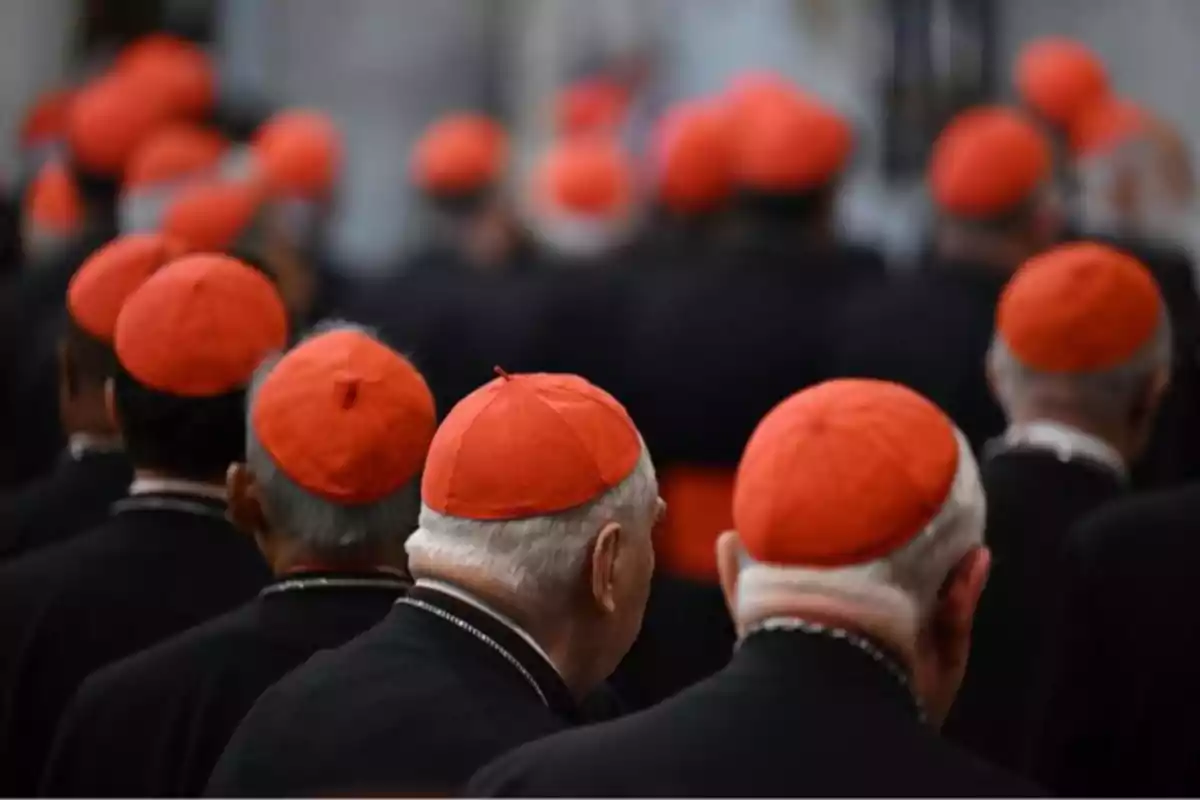 Un grupo de personas con birretes rojos en una ceremonia religiosa. Un grupo de personas con birretes rojos en una ceremonia religiosa.
