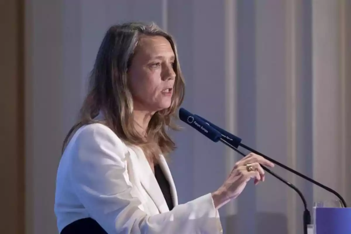 Una mujer hablando en un micrófono durante un evento. Una mujer hablando en un micrófono durante un evento.