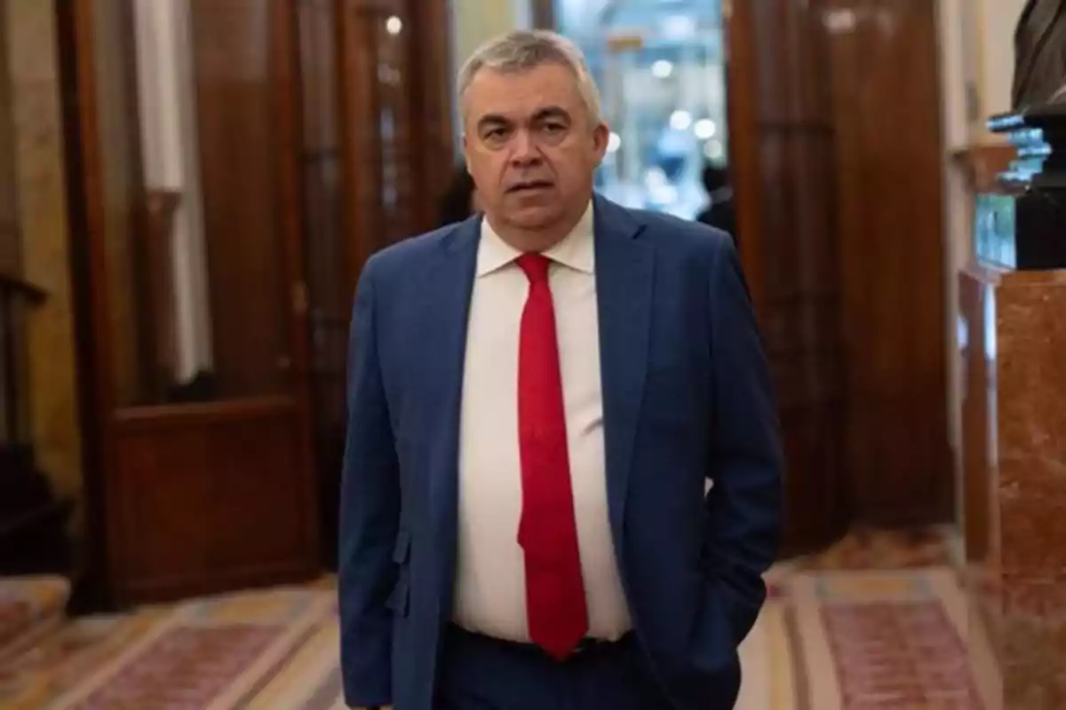 Hombre de cabello canoso con traje azul y corbata roja caminando en un pasillo elegante Hombre de cabello canoso con traje azul y corbata roja caminando en un pasillo elegante