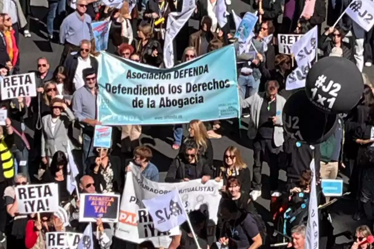 Un grupo de personas participa en una manifestación sosteniendo pancartas y globos que defienden los derechos de la abogacía.