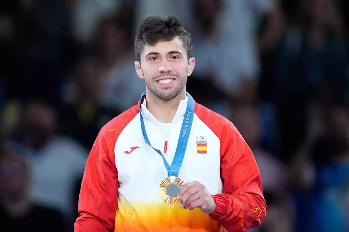 Un atleta sonriente con una medalla de plata en el cuello, vistiendo un uniforme deportivo con los colores de España.