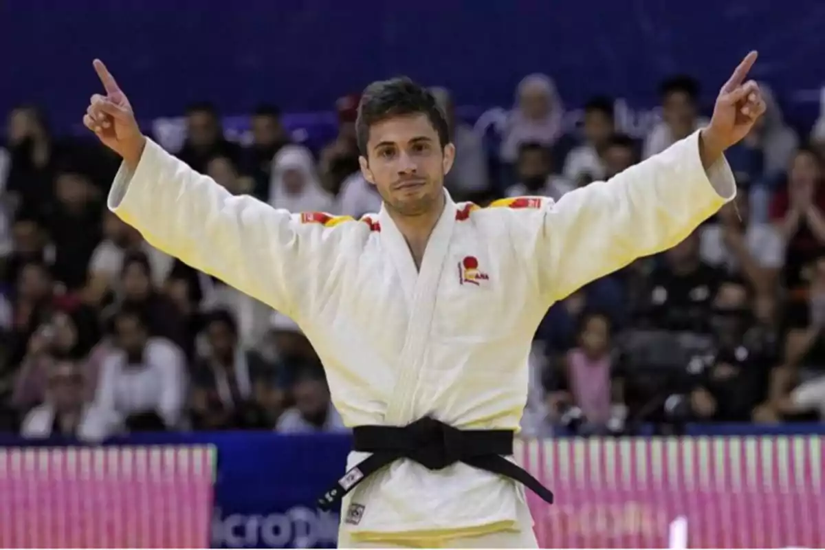 Judoka celebrando con los brazos extendidos en un evento deportivo.