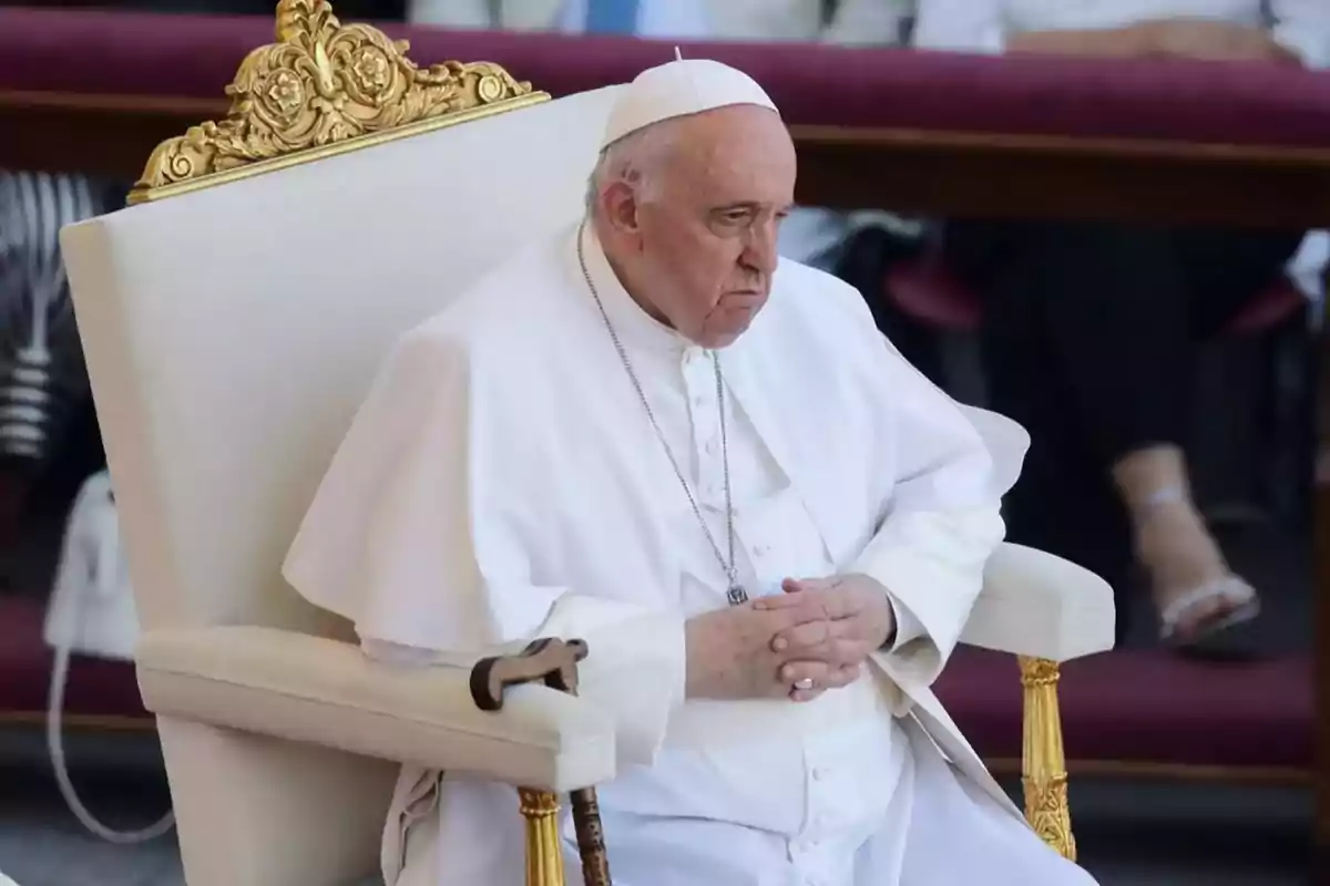 Una persona vestida con atuendo religioso blanco está sentada en una silla con detalles dorados.