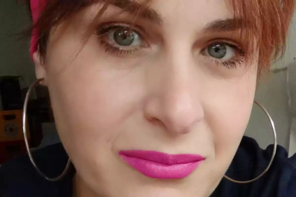 Mujer de cabello rojizo con labios pintados de rosa y aretes grandes mirando a la cámara Mujer de cabello rojizo con labios pintados de rosa y aretes grandes mirando a la cámara