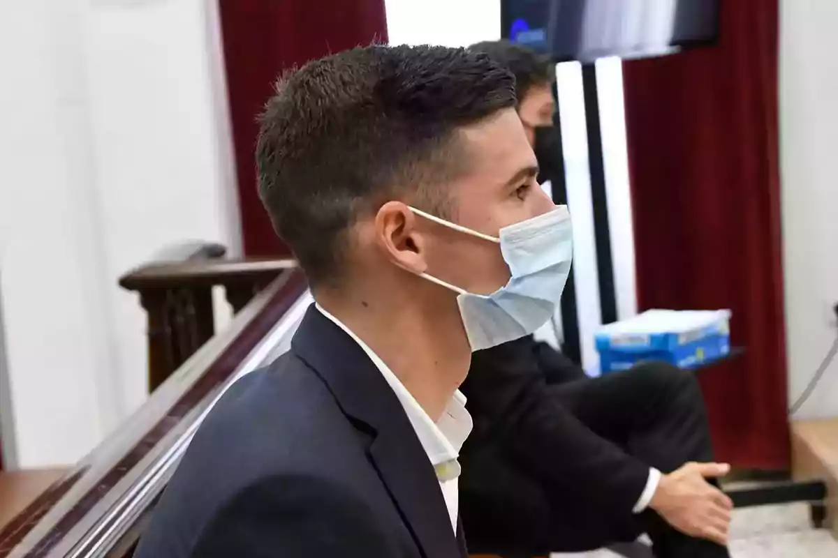 Un hombre con mascarilla sentado en una sala.