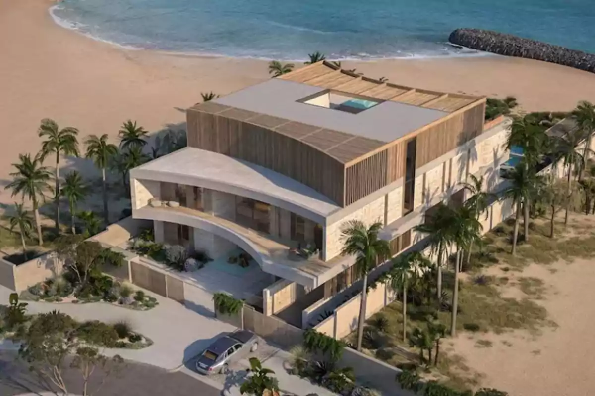 Vista aérea de una moderna casa de playa con diseño contemporáneo rodeada de palmeras y ubicada frente al mar.