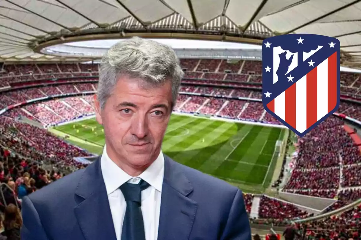 Hombre de traje frente a un estadio de fútbol lleno de espectadores con el escudo del Atlético de Madrid en la esquina.