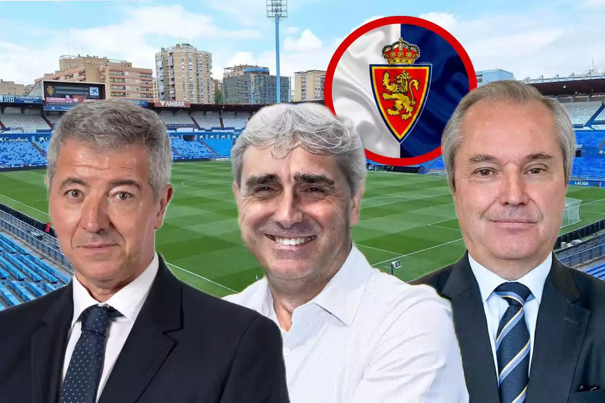 Tres hombres posan en primer plano dentro de un estadio de fútbol con gradas azules y el escudo del Real Zaragoza al fondo