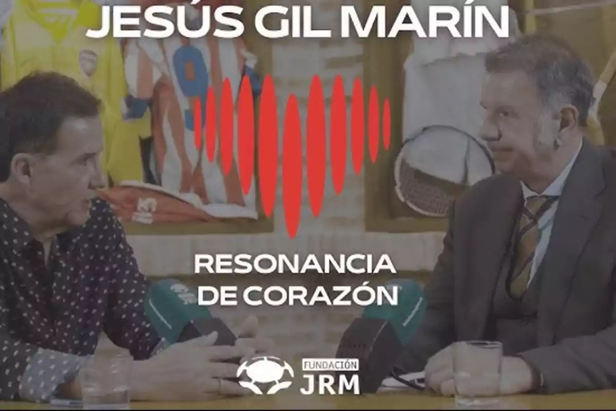 Dos hombres conversan en una entrevista con micrófonos sobre la mesa y camisetas deportivas de fondo, el texto en la imagen dice Jesús Gil Marín Resonancia de Corazón Fundación JRM Dos hombres conversan en una entrevista con micrófonos sobre la mesa y camisetas deportivas de fondo, el texto en la imagen dice Jesús Gil Marín Resonancia de Corazón Fundación JRM
