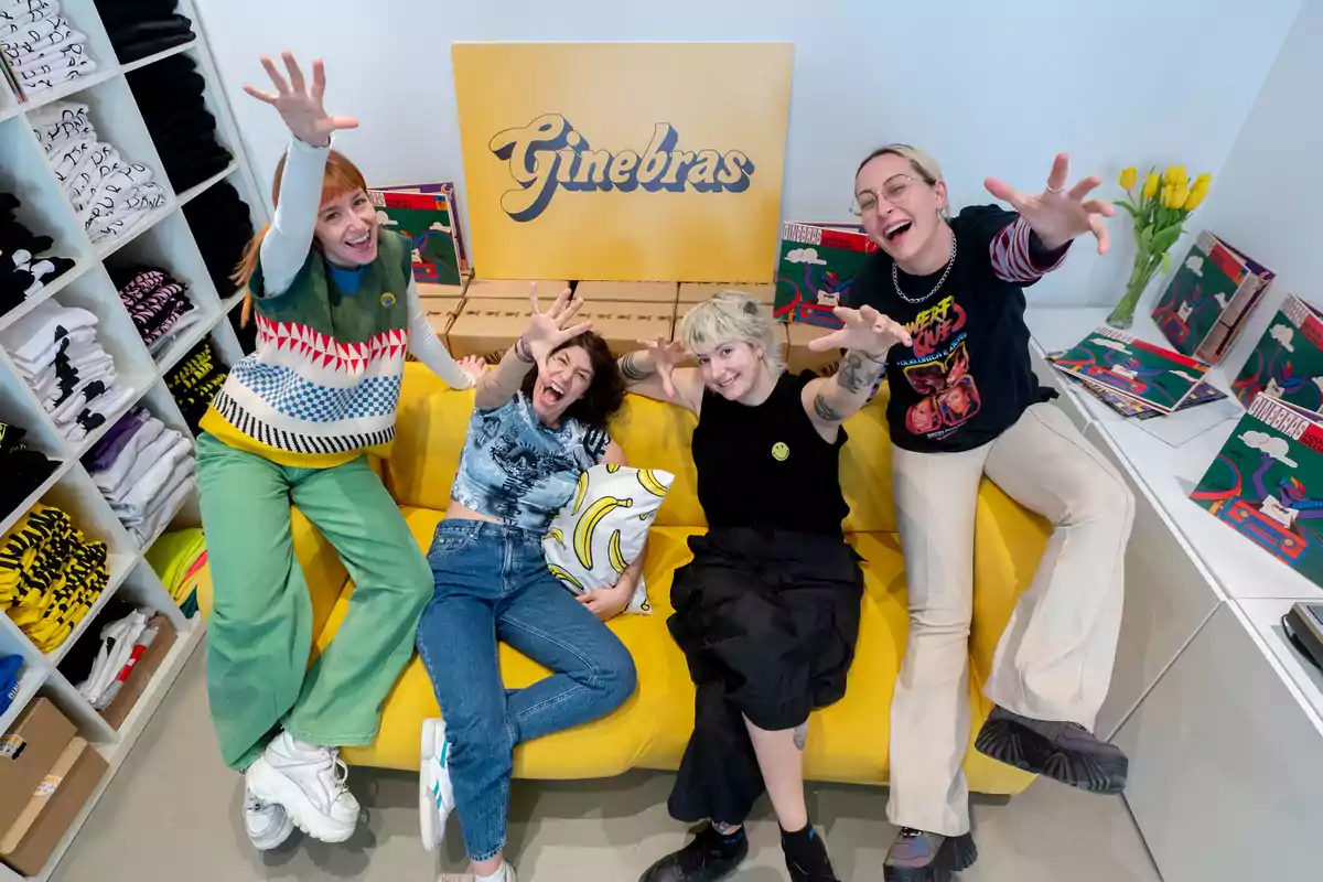 Un grupo de personas sonrientes posando con entusiasmo en un sofá amarillo, rodeadas de productos y un cartel que dice "Ginebras".