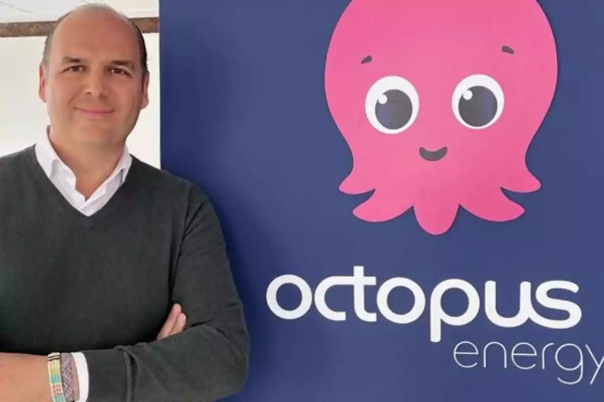 Hombre de pie junto a un cartel de Octopus Energy con un pulpo rosa sonriente.