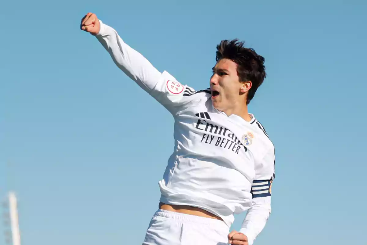 Futbolista del Real Madrid celebrando un gol con el puño en alto bajo un cielo despejado Futbolista del Real Madrid celebrando un gol con el puño en alto bajo un cielo despejado