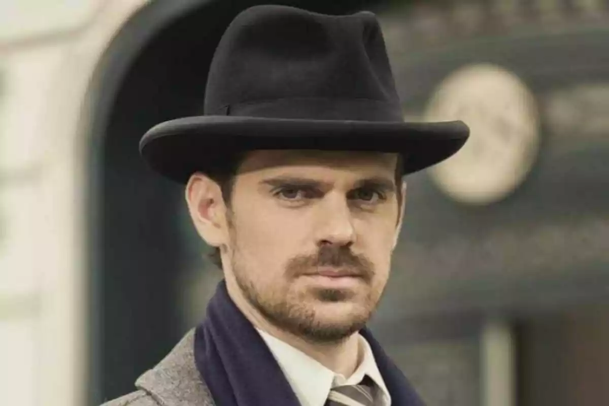 Gonzalo Ramos con sombrero negro y barba, vistiendo un abrigo y corbata, mira hacia la cámara con expresión seria. Gonzalo Ramos con sombrero negro y barba, vistiendo un abrigo y corbata, mira hacia la cámara con expresión seria.