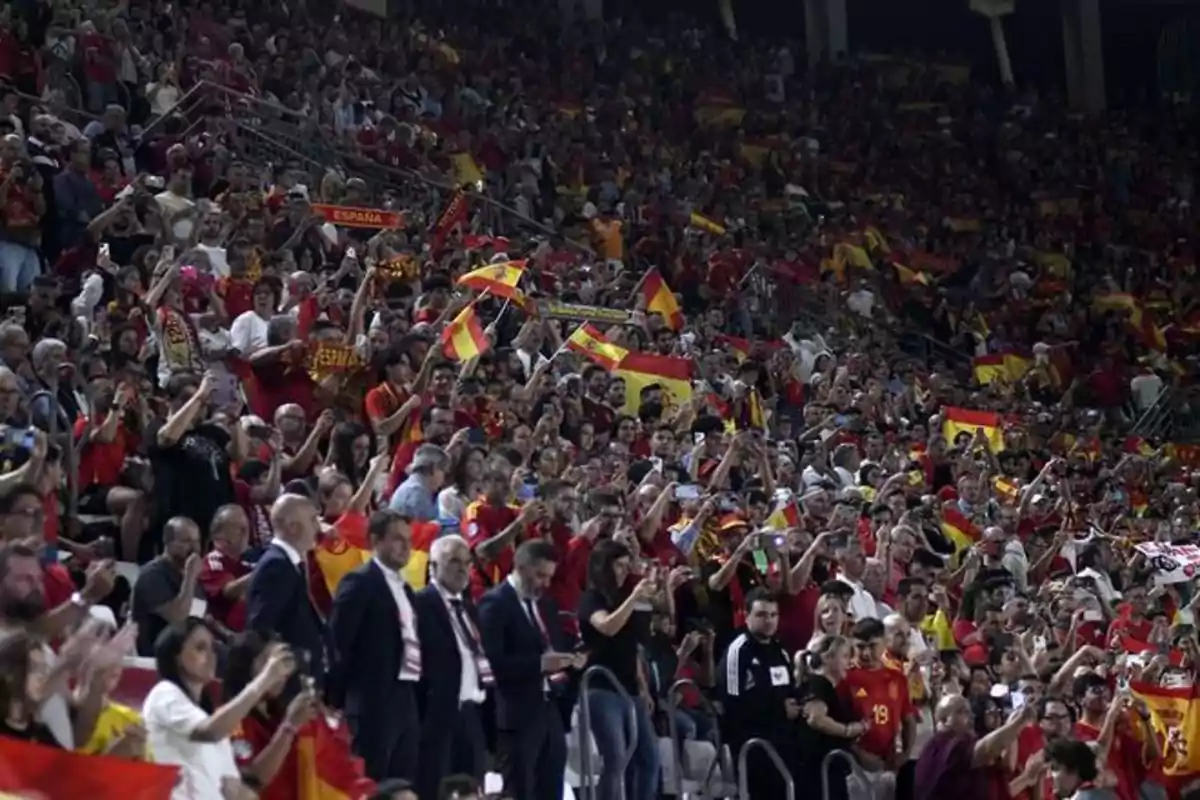 Una multitud de personas en un estadio animando con banderas de España.